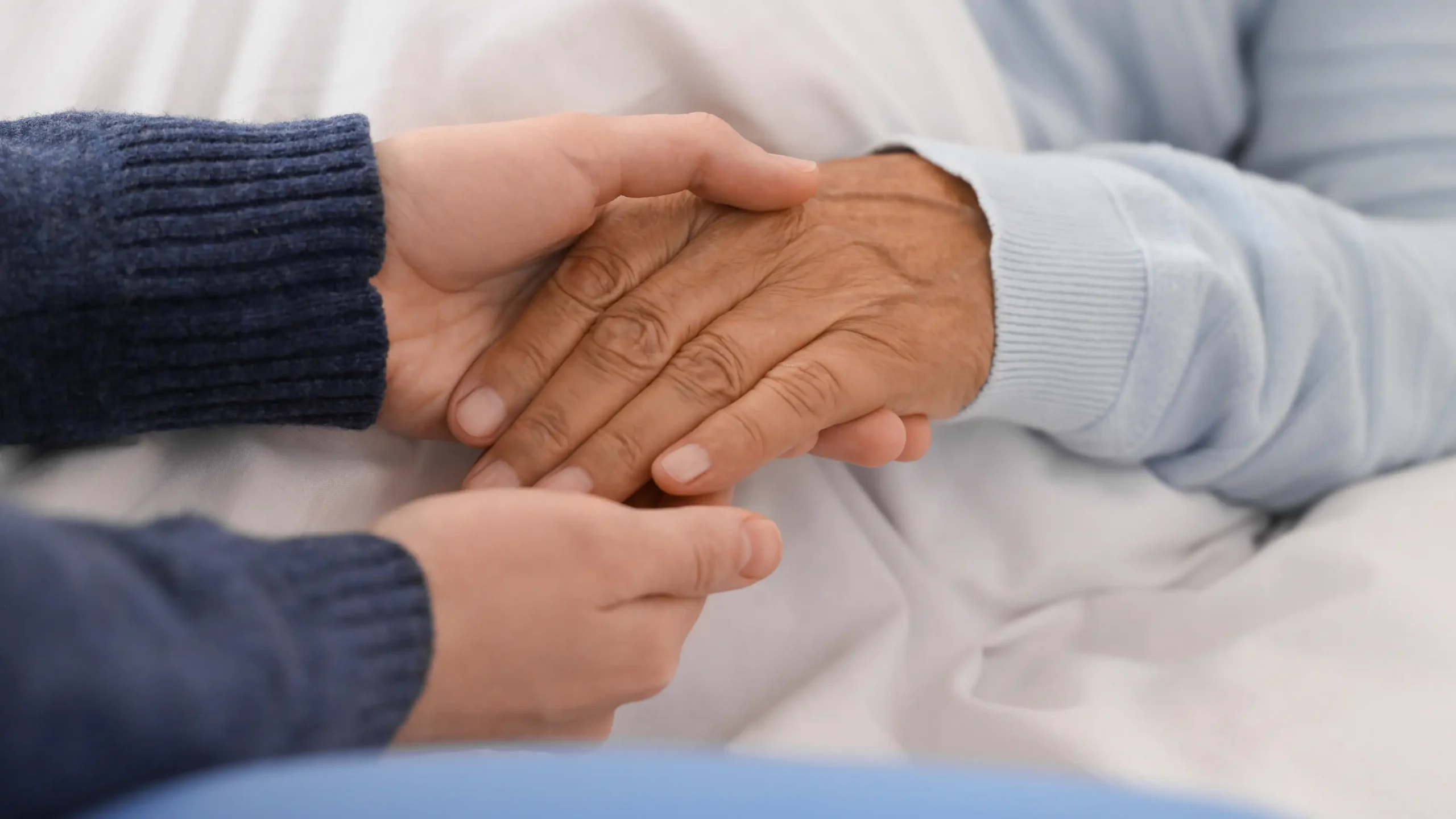 Caregiver assisting a senior man in a home-care bed, providing support during the process of voluntary assisted dying and end of life in Melbourne